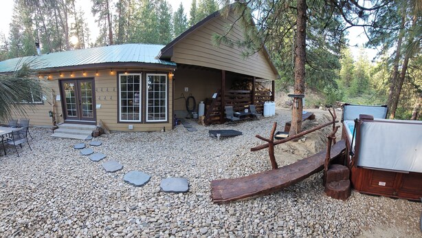 Une cabane rustique avec un toit en métal, une terrasse en bois et un sol en gravier.