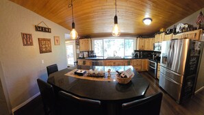 Une cuisine avec des meubles en bois, un réfrigérateur en acier inoxydable et une table à manger avec des chaises.