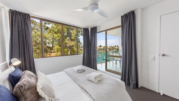 Ein Hotelzimmer mit Bett, Schreibtisch, Stuhl und Blick auf Pool und Bäume.