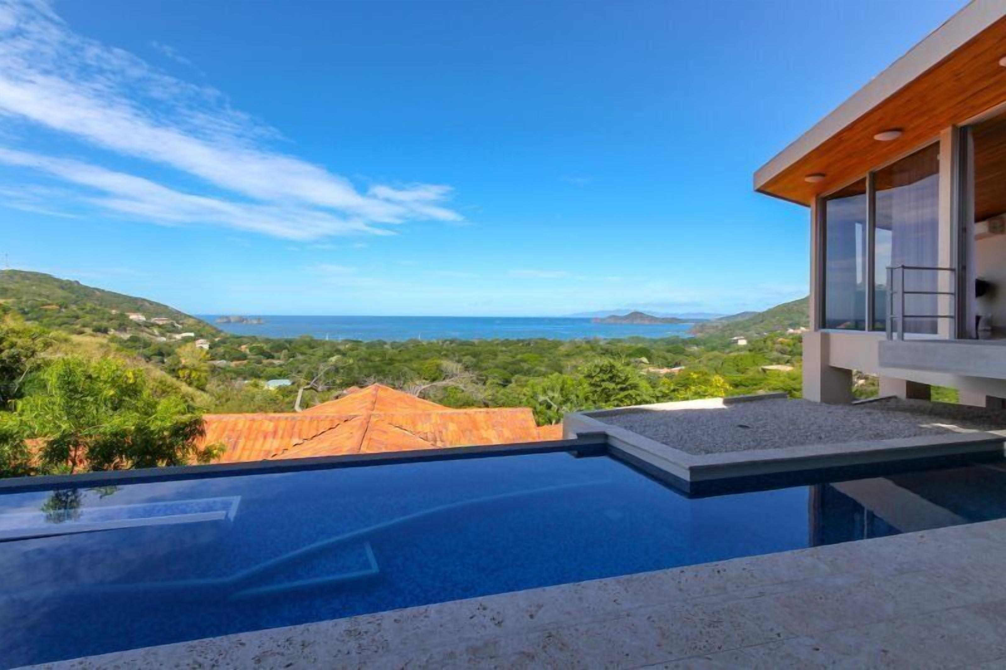 Una casa moderna con una piscina grande que domina un paisaje pintoresco.