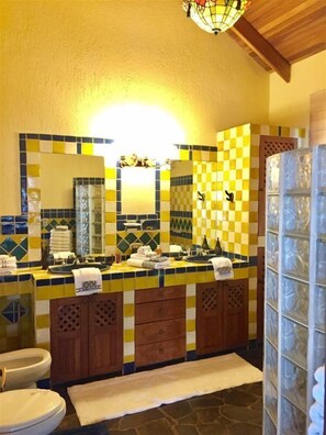 A bathroom with a checkered tile backsplash, wooden cabinets, and a glass shower enclosure.