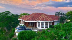 A house with a red-tiled roof, a swimming pool, and lush greenery surrounding it. - Casita Cole (Sardinal)