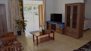 Een woonkamer met een televisie, een houten kast en een bank.