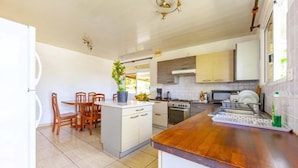 Een moderne keuken met een centraal eiland, houten stoelen, een eettafel en een ingebouwde oven.
