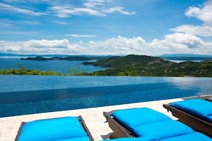 A poolside area with lounge chairs and a view of a lake and hills. - Los Sueños (Sardinal)