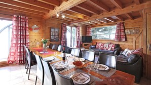 Una cabaña de madera con comedor, asientos de cuero y televisor.