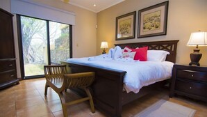 A bedroom with a bed, a desk, and a chair. There are two lamps on either side of the bed. - Mariners Point - C1 (Sardinal)