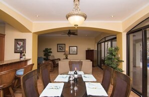 Een eetgedeelte met een ronde tafel voor vier personen, een plafondventilator en een kroonluchter.