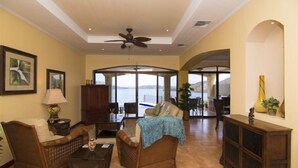 A spacious living room with a large window offering a view of the sea. There are two wicker sofas, a coffee table, and a cabinet. - Mariners Point - C1 (Sardinal)