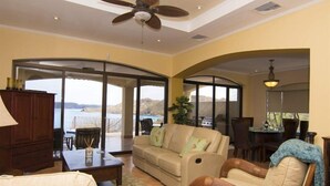 A spacious living room with a large sofa, a dining table, and a ceiling fan. - Mariners Point - C1 (Sardinal)