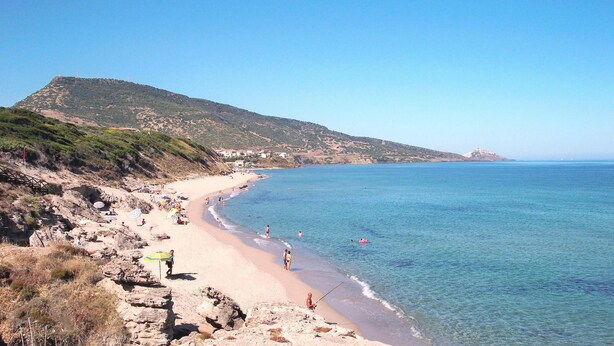 A beach with rocky terrain, a clear blue sea, and a distant hill with buildings. - Terrazze sul Mare Alla Ciaccia - Apartment 5 (Valledoria)
