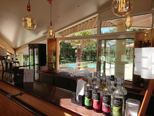 A bar area with a view of a pool and greenery outside.