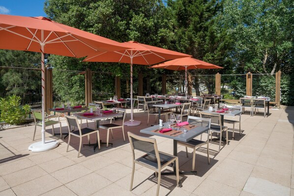 An outdoor patio with tables and chairs, some with umbrellas.