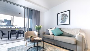 Una sala de estar moderna con un sofá gris, una mesa de centro redonda y un comedor con sillas y una mesa.