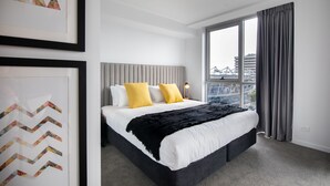 Un hotel moderno con una cama grande, vistas a la ciudad y una obra de arte enmarcada en la pared.