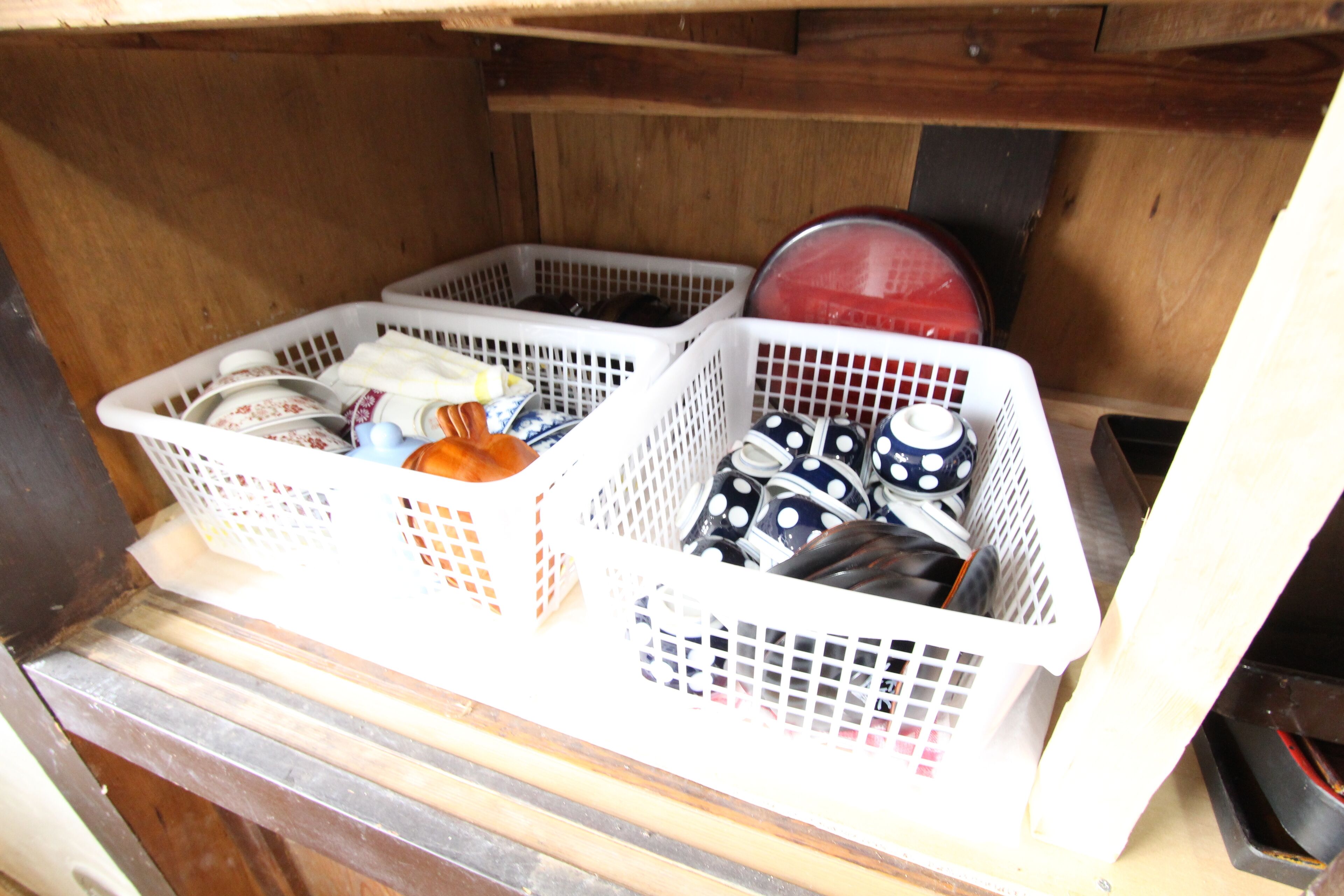 A storage area with white baskets containing kitchenware.