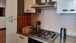 A kitchen with white cabinets, a stainless steel range hood, a tiled backsplash, and a gas stove. - Appartamento a Invrea Posto Auto Incluso (Genoa)