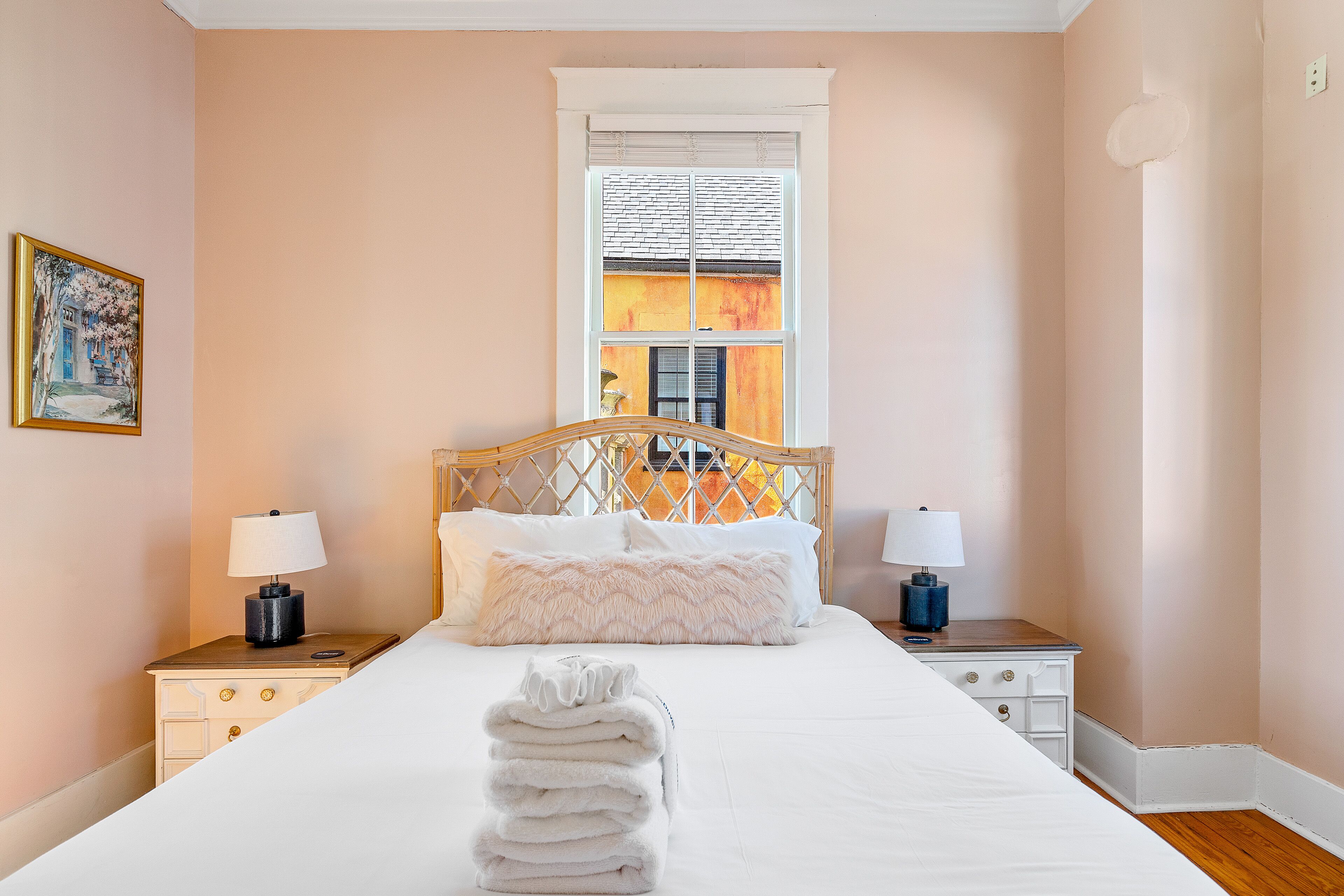 Un lit bien fait, avec du linge de lit blanc, une pile de serviettes pliées et deux tables de chevet avec des lampes.