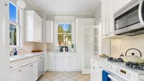 A modern kitchen with white cabinetry, a gas stove, and a microwave. - Elegance Meets Ease in Historic CHS | The Rosewood (Charleston)