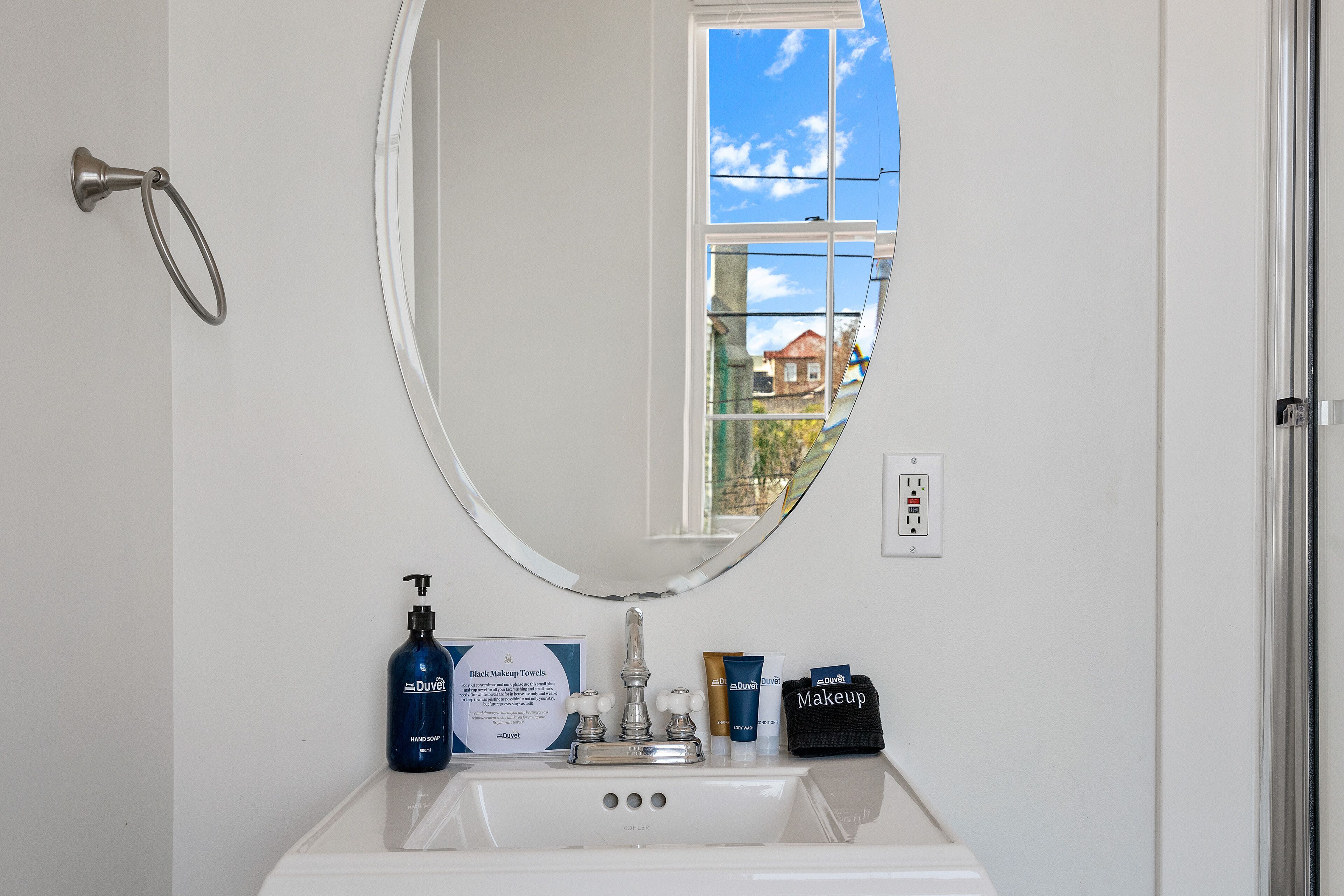 A bathroom with a white sink, a mirror, and toiletries.