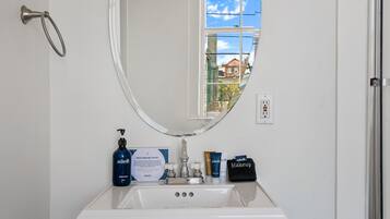 A bathroom with a white sink, a mirror, and toiletries.
