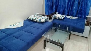 Ein Zimmer mit zwei blauen Sofas, einem Glastisch und einem blauen Vorhang.