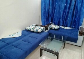 A room with two blue sofas, a glass coffee table, and a blue curtain.