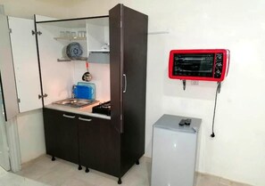 Réfrigérateur, un four, surface de cuisson, vaisselle et ustensiles