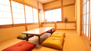 A traditional Japanese room with tatami flooring, a low table, cushions, and sliding doors. - Gran Kodachi (Fujikawaguchiko)