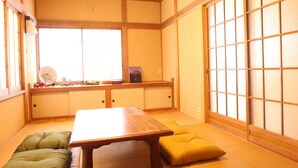 A traditional Japanese room with tatami flooring, a low table, cushions, sliding doors, and a clock on the wall. - Gran Kodachi (Fujikawaguchiko)