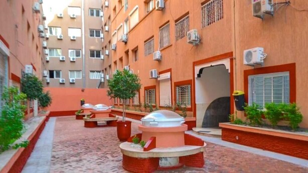 Un cortile con zone salotto all'aperto, un elemento d'acqua e un edificio con numerose finestre e condizionatori.