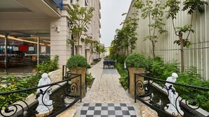 A narrow pathway with a checkered floor leading to a seating area, flanked by buildings and greenery. - Menippe Hotel (Kaohsiung)