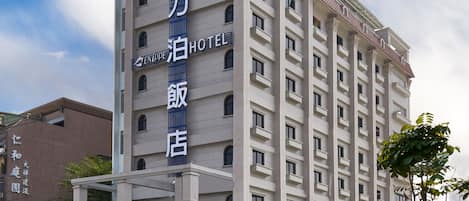 Un hotel con un letrero llamativo, una entrada bien cuidada y un cielo despejado.
