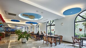A modern restaurant with high ceilings, blue accents, and large windows. - Menippe Hotel (Kaohsiung)