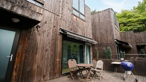 A wooden exterior with a glass door and a patio area with a table and chairs.