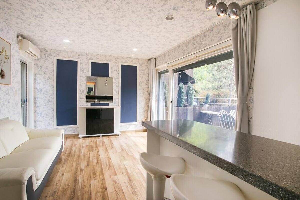 Uma cozinha moderna com forno embutido, um espaço de refeições com mesa e cadeiras brancas e uma grande janela com vista para o exterior.
