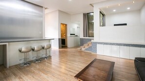A modern kitchen with a bar area, wooden flooring, and a dining table.