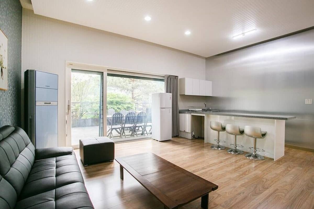 Uma sala de estar moderna com sofá, mesa de centro e área de cozinha com balcão e banquetas.