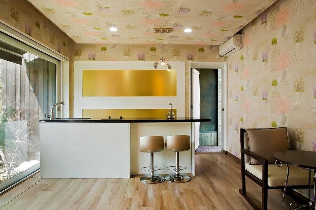 Uma cozinha moderna com uma ilha central, banquetas de bar e uma área de refeições com mesa e cadeiras.