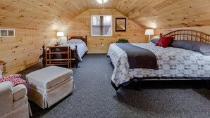 Un dormitorio acogedor en el ático con dos camas, un ventilador de techo y una ventana.