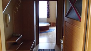 Un pasillo estrecho que conduce a un dormitorio con cama y ventana.