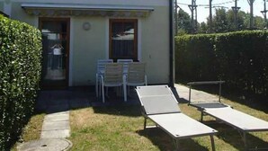 Una casa de dos pisos con un patio cubierto, un jardín pequeño y una piscina.