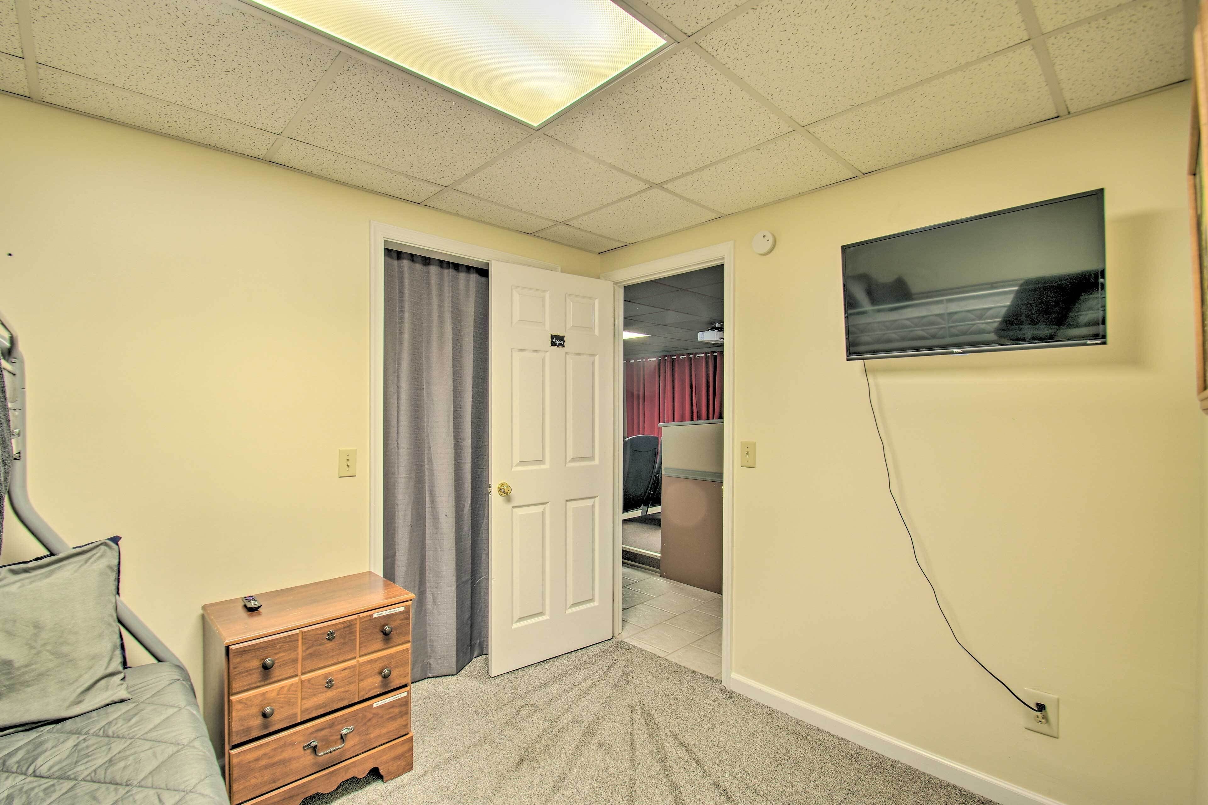 A bedroom with a bed, dresser, and a door leading to another room.