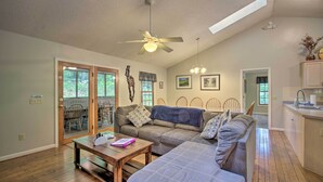 A spacious living room with a ceiling fan, a sofa, a coffee table, and a dining area with chairs. - 17-Seat Home Theater, Hot Tub, Huge Game Room! (Massanutten)