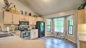 A kitchen with a large island, stainless steel appliances, and a dining area with two chairs and a table. - 17-Seat Home Theater, Hot Tub, Huge Game Room! (Massanutten)