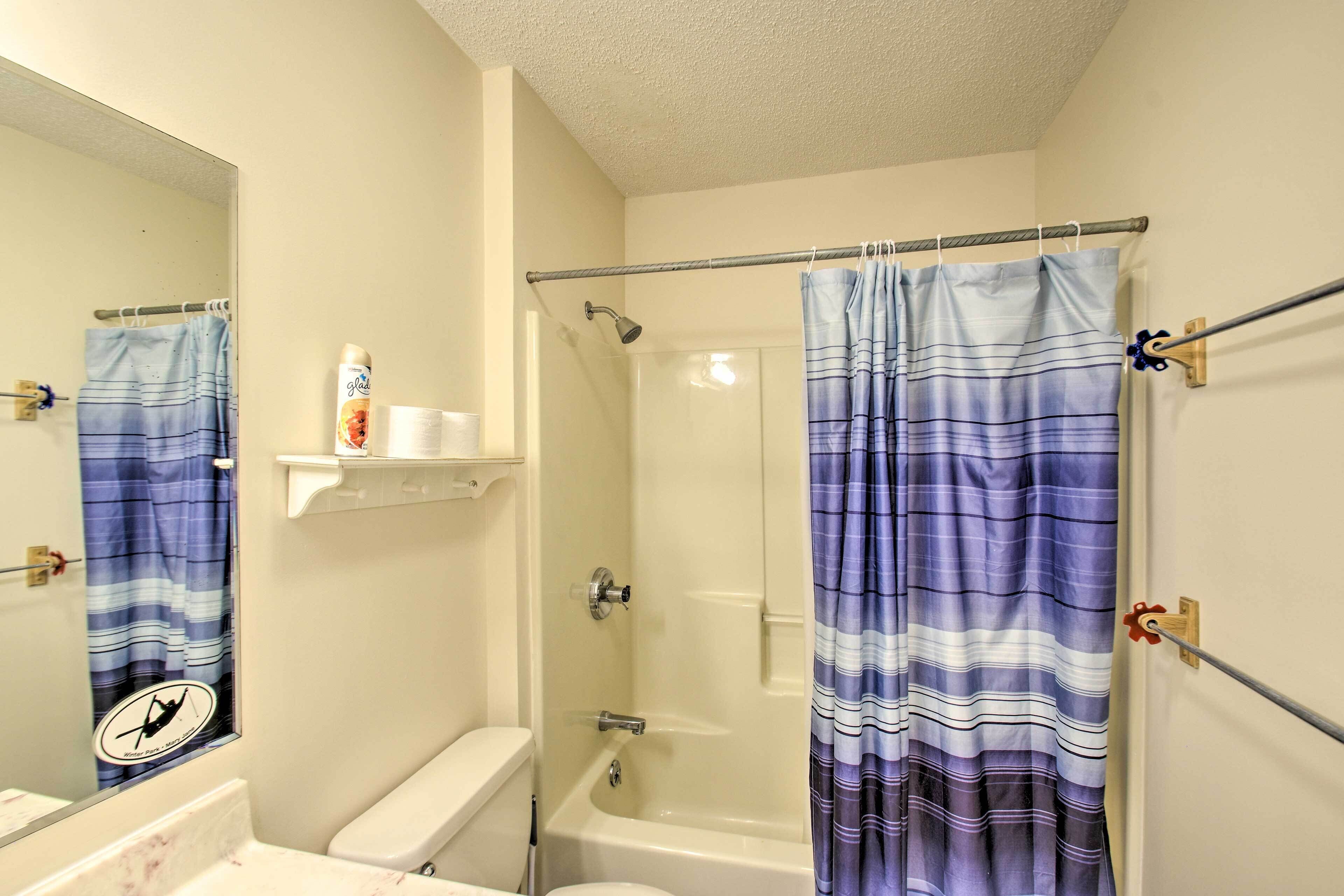 A bathroom with a shower, toilet, and a mirror.