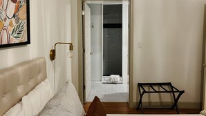 A bedroom with a bed, a bedside table, a chair, a door leading to a bathroom, and a wall-mounted light fixture. - Steps to Lane And VT Campus Cozy 2 bed/2 bath Blacksburg Apartment (Blacksburg)