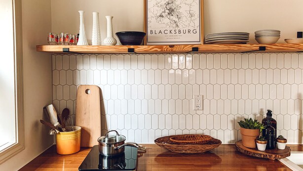 A kitchen with a wooden shelf holding various items, a hexagonal tiled backsplash, and a countertop with a portable stove. - Steps to Lane And VT Campus Cozy 2 bed/2 bath Blacksburg Apartment (Blacksburg)