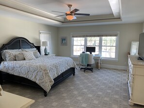 Ein Schlafzimmer mit einem Bett, einem Schreibtisch, einem Stuhl, einer Kommode und einem Deckenventilator.