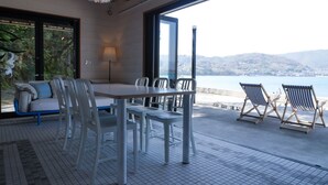 Ein moderner Essbereich mit großem Tisch und Stühlen, einer Couch und Blick auf das Meer.